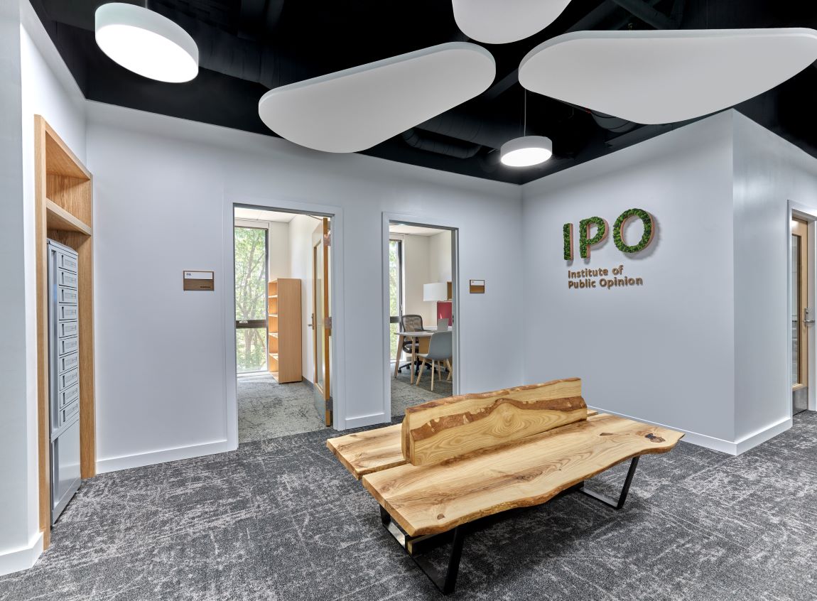 Inside of a building showing an rustic bench and doorways opening to offices.